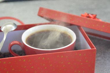 Bir fincan kahve dolu içinde kahve çekirdekleri ile bir Noel hediye kutusunda - kahve noel için bir tedavi ve hediye olarak güzel paketlenmiş 