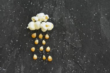 Papa bir Mısır - bulut ile yağmur gibi patlamış mısır ve siyah bir arka plan ve şeker taneleri önünde Mısır üzerinden patlamış mısır patlamış mısır ve Mısır - konseptiyle yağmurlar