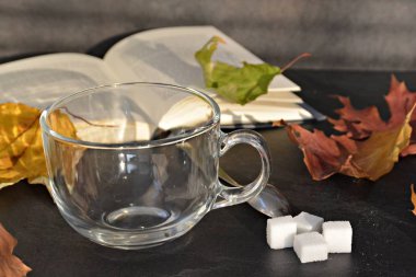 Bir cam fincan içine bir sonbahar ayarı kahve dökün-bir cam fincan kuru ve renkli sonbahar yaprakları ve arka planda bir kitap yanında standig ve birisi içine kahve dökme olduğunu