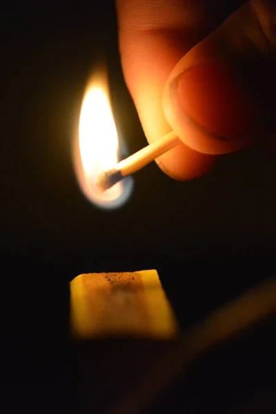 Igniting a match in the dark on a matchbox - Close-up of a lighting match in the night - Match lit up the night
