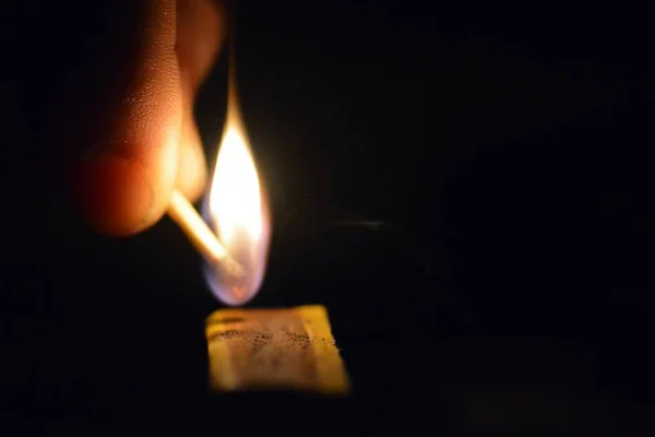 Igniting a match in the dark on a matchbox - Close-up of a lighting match in the night - Match lit up the night