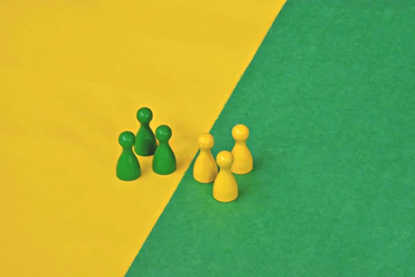 team of wooden game characters of a board game face each other and are greeted by the respective oppositely colored background