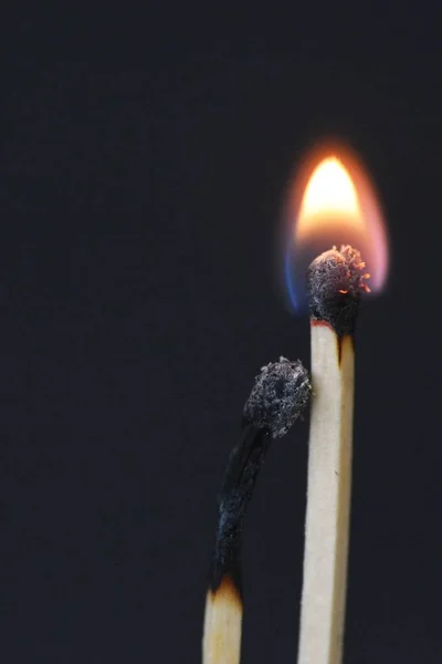 Two burned matches against a black background look like a couple cuddling and being intimate with each other - concept symbolizing fiery love