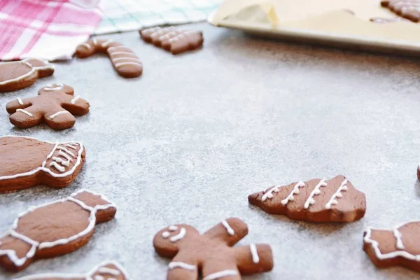 Home-baked gingerbread biscuits in a variety of shapes and decorated with white sugar mass lie on a kitchen surface with space for text or elements - Gingerbread frame for Christmas