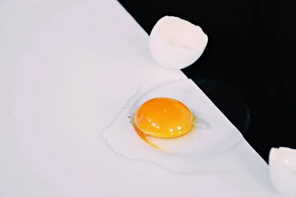 卵白に囲まれた無傷の卵黄を持つ開いた卵は 半分黒い半分の白い背景に横たわっている 黒と白と卵の概念 — ストック写真