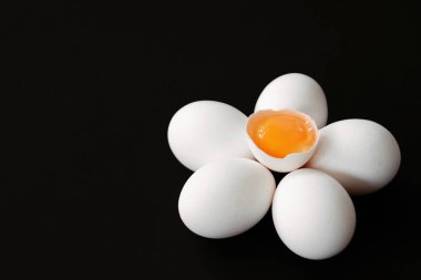 Siyah bir arka plan ve taze yumurta ve koyu arka plan ile bir çiçek-kavramı olarak merkezinde yumurta sarısı ile çırpılmış bir yumurta ile beyaz yumurta bir çiçek