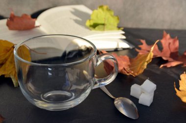 Bir cam fincan içine bir sonbahar ayarı kahve dökün-bir cam fincan kuru ve renkli sonbahar yaprakları ve arka planda bir kitap yanında standig ve birisi içine kahve dökme olduğunu