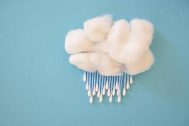 Pamuk gibi bir yün ve kulak çubukları mavi bir arka plan üzerinde yağmur ya da kar olarak-pamuk bez ve pamuk topları ile yağmur veya hızlı kavramı