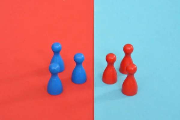 ボードゲームの木製のゲームキャラクターの赤と青のチームは お互いに直面し それぞれの反対色の背景によって迎えられています 境界と違いの概念 — ストック写真