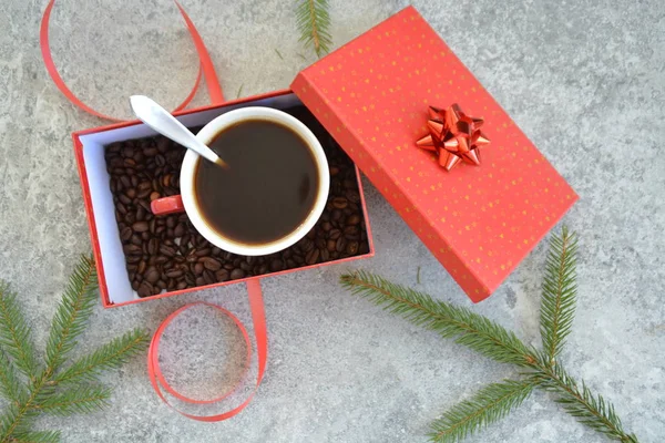 A cup full of coffee is in a Christmas gift box with coffee beans in it - coffee as a treat and gift for Christmas nicely packaged