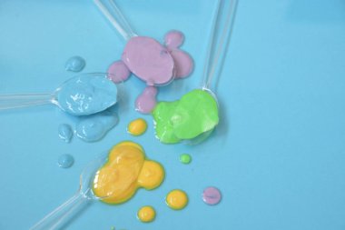 Düz bir arka planda boya farklı damla ile şeffaf kaşıklar-metin alanı ile arka plan olarak renk ile plastik kaşık 