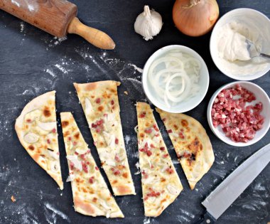 Yakın çekim-adam siyah mutfak yüzeyinde bir ev yapımı Alsas tarte pasta keser-yanında tarte flambe için malzemeler vardır