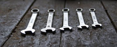 Anahtarların çeşitli boyutları, anahtarı ön ucunda odak ile karanlık çevrede arkasında pozlama ile ahşap bir tezgah üzerinde yatıyor 