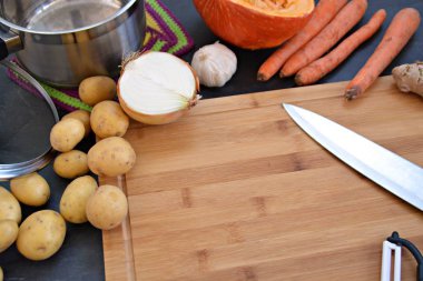 Havuç, patates, soğan, sarımsak ve ahşap bir tahta üzerinde kabak çorbası için bir kabak için sebze kesme ve yukarıda elleri üzerinde pot-closeup içine dökme