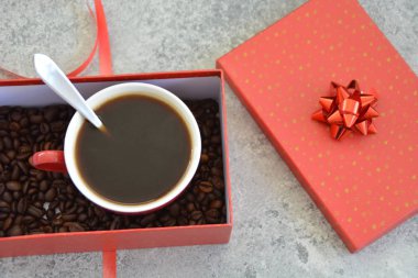 Bir fincan kahve dolu içinde kahve çekirdekleri ile bir Noel hediye kutusunda - kahve noel için bir tedavi ve hediye olarak güzel paketlenmiş 