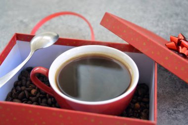 Bir fincan kahve dolu içinde kahve çekirdekleri ile bir Noel hediye kutusunda - kahve noel için bir tedavi ve hediye olarak güzel paketlenmiş 