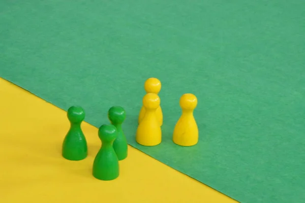 team of wooden game characters of a board game face each other and are greeted by the respective oppositely colored background