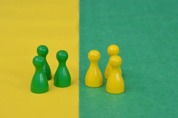 team of wooden game characters of a board game face each other and are greeted by the respective oppositely colored background