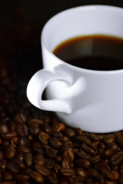コーヒーへの愛を描いたミニマリストのコンセプト コーヒーの中のカップのハンドルの影とコーヒー豆の上に立つものは 光の影の中でハートのように見えます — ストック写真