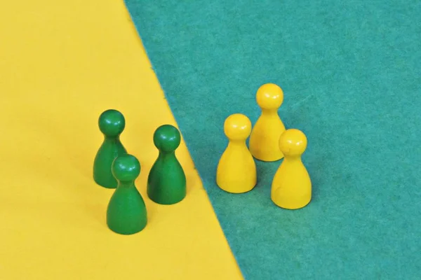 team of wooden game characters of a board game face each other and are greeted by the respective oppositely colored background