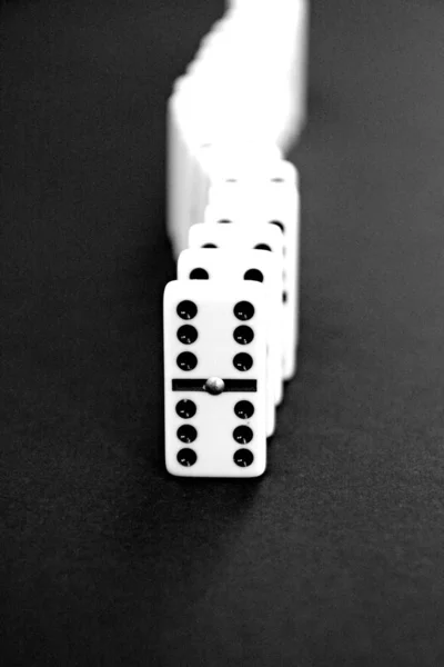 Bright dominoes against a black background with shallow depth of field as a concept for business concepts and subsequent reactions of individual decisions and individual actions