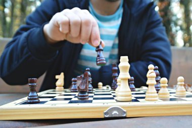 Onun orta yirmili bir adam bir otumnal parkta oturur ve satranç oynar-gemide oyun parçaları odaklanmak, kişi görülebilir ve sadece eller ve gövde görülebilir