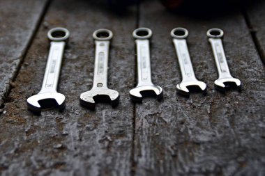 Anahtarların çeşitli boyutları, anahtarı ön ucunda odak ile karanlık çevrede arkasında pozlama ile ahşap bir tezgah üzerinde yatıyor 