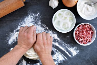 Yakın çekim-adam siyah mutfak yüzeyinde bir Alsas tarte pasta için hamur dışarı rulo-yanında tarte flambe için maddeler vardır