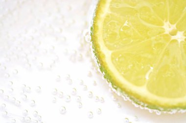 Beyaz arka planda gazlı suda bir kireç ile bir kireç kabuğu üzerinde hava kabarcıkları formu-su kireç yakın çekim