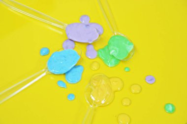 Düz bir arka planda boya farklı damla ile şeffaf kaşıklar-metin alanı ile arka plan olarak renk ile plastik kaşık 