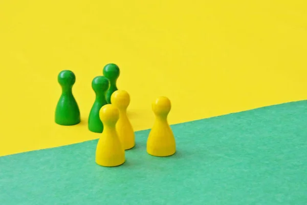 team of wooden game characters of a board game face each other and are greeted by the respective oppositely colored background