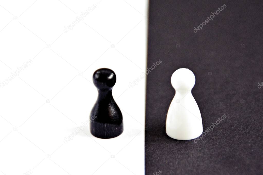 A black pawn stands in front of a white background and vice versa - concept with strong contrasts as a symbol of differences and equality, as well as ying and yang