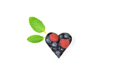 Kurabiye kesici nane ile beyaz bir arka plan önünde yaban mersini ve ahududu ile dolu-çerez formunda taze çilek ile kavramı yanında yaprakları 