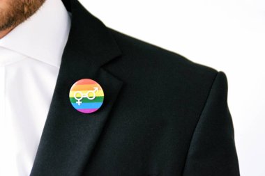 20'li yaşlarının ortasında bir adam takım ceketinde transseksüel sembolü olan bir düğme takıyor - Çalışma Hayatında Kabul ve Hoşgörü Kavramı