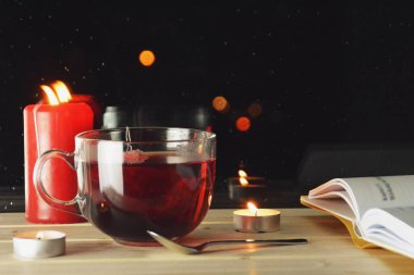 Gece ışıkları görülebilir bir yağmur ıslatılmış pencerenin önünde gece ahşap pencere üzerinde duran meyve çayı büyük bir bardak-çay bir fincan rahat yağmurlu gece