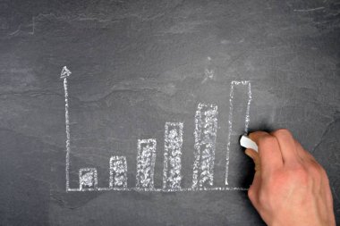 Ekonomik bağlamda istatistik ve değerlendirmeler için tebeşir konsepti ile çizilmiş siyah mermer yüzeyde bir ayaklanma şeması 