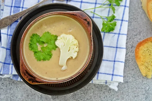 Taze yapılmış ev yapımı karnabahar çorbası maydanoz ve tost beyaz ekmek ile ot tereyağı yayılmış bir mutfak yüzeyi-sağlıklı ve vejetaryen öğle yemeği ile karnabahar ve krem