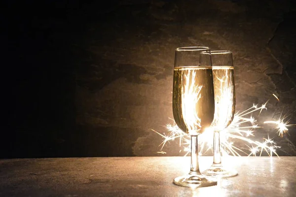 Dva Plněné Šampaňské Tmě Stojí Před Třpytem Který Osvětluje Jiskřičkami — Stock fotografie