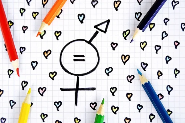 A sign for the equality of man and woman consisting of the respective gender signs and a match with painted hearts and colored pencils on a drawn sheet -equality man and woman symbolically represented