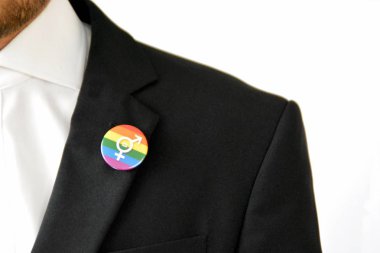 20'li yaşlarının ortasında bir adam takım ceketinde transseksüel sembolü olan bir düğme takıyor - Çalışma Hayatında Kabul ve Hoşgörü Kavramı