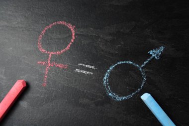 Karanlık bir mermer yüzeyde, erkek ve kadın sembolü farklı Chalks ve aralarında gerçek bir maç ile kaydedildi-erkek ve kadınların eşitlik için kavramı 