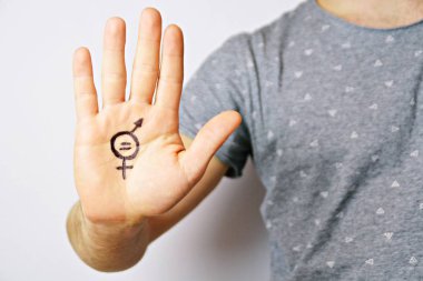 Onun orta yirmili bir adam elinde cinsiyet eşitliği bir işareti boyalı ve kamera gösterir-erkek ve kadınlar arasında eşitlik talep için bir kavram 