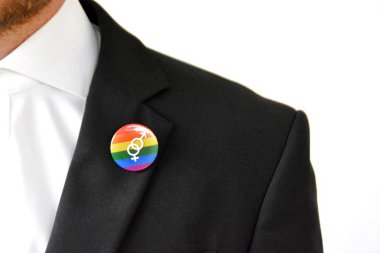 20'li yaşlarının ortasında bir adam takım ceketinde transseksüel sembolü olan bir düğme takıyor - Çalışma Hayatında Kabul ve Hoşgörü Kavramı