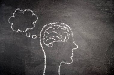 Düşünce süreci için bir kavramı ve sembolü olarak karanlık bir taş yüzey üzerinde tebeşir ile çizilmiş bir kafa silüeti ve yaratıcılık ve problem çözme unfolding için beyin fırtınası 