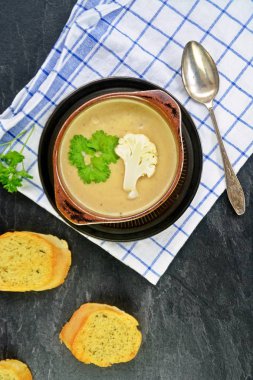Taze yapılmış ev yapımı karnabahar çorbası maydanoz ve tost beyaz ekmek ile ot tereyağı yayılmış bir mutfak yüzeyi-sağlıklı ve vejetaryen öğle yemeği ile karnabahar ve krem