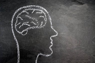 Düşünce süreci için bir kavramı ve sembolü olarak karanlık bir taş yüzey üzerinde tebeşir ile çizilmiş bir kafa silüeti ve yaratıcılık ve problem çözme unfolding için beyin fırtınası 