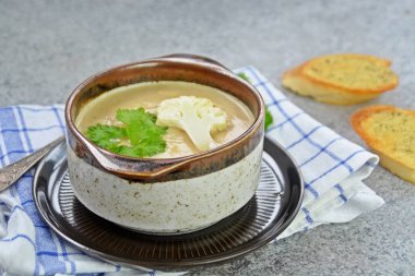 Taze yapılmış ev yapımı karnabahar çorbası maydanoz ve tost beyaz ekmek ile ot tereyağı yayılmış bir mutfak yüzeyi-sağlıklı ve vejetaryen öğle yemeği ile karnabahar ve krem