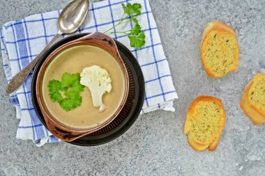 Taze yapılmış ev yapımı karnabahar çorbası maydanoz ve tost beyaz ekmek ile ot tereyağı yayılmış bir mutfak yüzeyi-sağlıklı ve vejetaryen öğle yemeği ile karnabahar ve krem