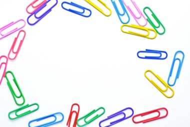 Çeşitli renkli kağıt klipler beyaz bir yüzey üzerinde yatıyor-bir arka plan beyaz bir taban ve renkli ataç oluşan