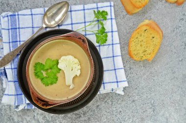 Taze yapılmış ev yapımı karnabahar çorbası maydanoz ve tost beyaz ekmek ile ot tereyağı yayılmış bir mutfak yüzeyi-sağlıklı ve vejetaryen öğle yemeği ile karnabahar ve krem